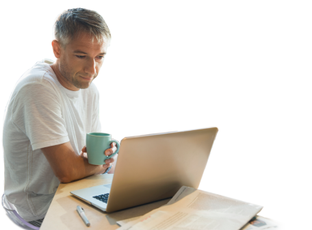 A man drinking coffee while reading on his laptop